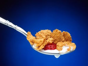 Spoonful of cereal flakes with strawberries and milk
