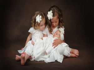 Two little girls holding a baby
