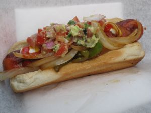 Hot dog with onion, guacamole and bacon