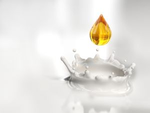 Amber colored drop falling in the milk